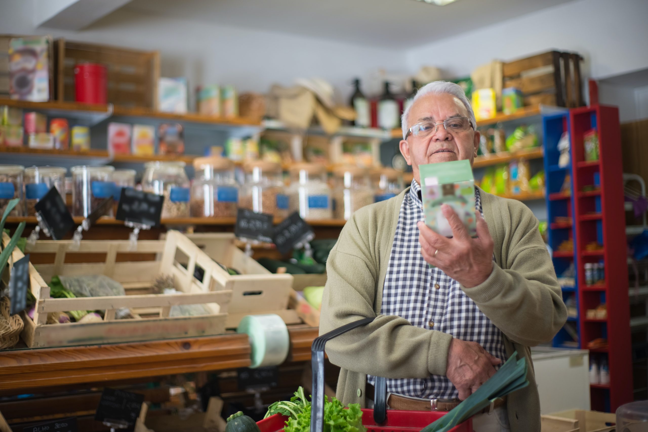 Photo d'un homme âge dans un magasin en train de lire l'étiquette d'un packaging
